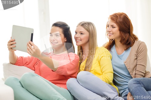 Image of three smiling teenage girls with tablet pc at home