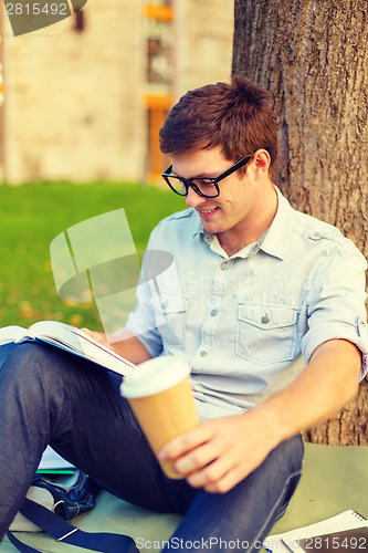 Image of teenager reading book with take away coffee
