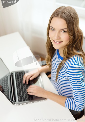 Image of smiling teenage gitl with laptop computer at home