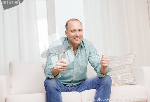 Image of smiling man watching sports at home