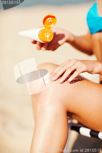 Image of girl putting sun protection cream on beach chair