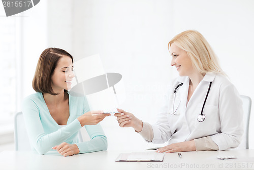 Image of doctor giving tablets to patient in hospital