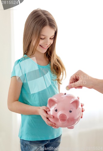 Image of smiling little girl holding piggy bank