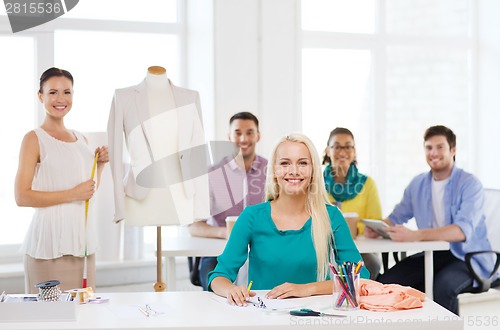 Image of smiling fashion designers working in office