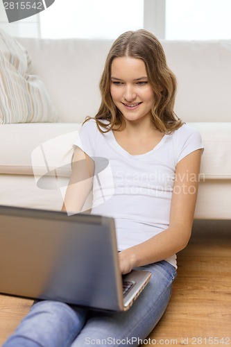 Image of smiling teenage girl with laptop computer at home