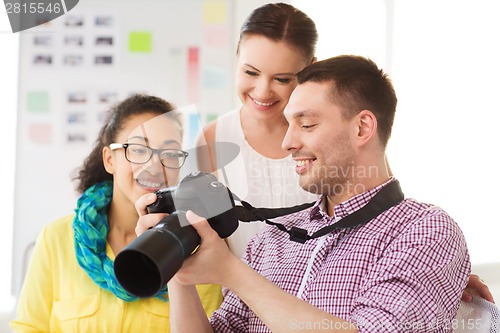 Image of smiling team with photocamera working in office