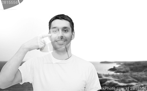 Image of smiling young handsome man pointing to eyes