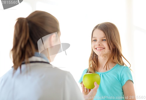 Image of female doctor giving apple to smiling little girl