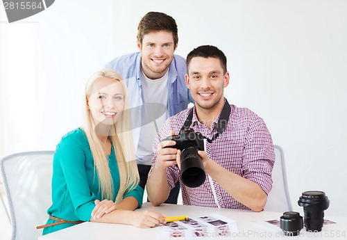 Image of smiling team with photocamera working in office