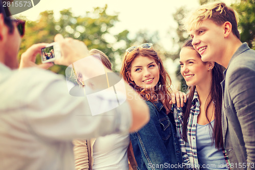 Image of teenagers taking photo with digital camera outside