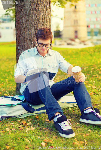 Image of teenager reading book with take away coffee