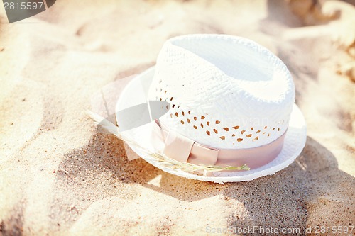 Image of white straw hat lying in the sand on the beach