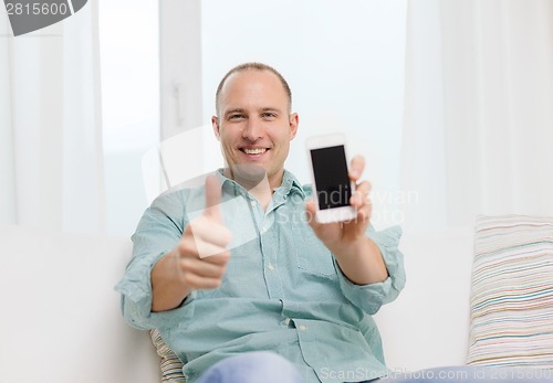 Image of smiling man with smartphone at home