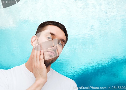 Image of beautiful calm man touching his face