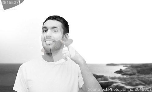 Image of smiling young handsome man pointing to cheek