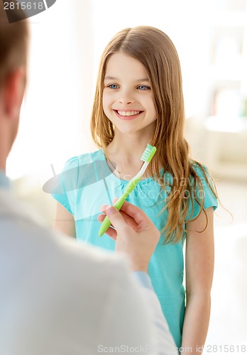 Image of male doctor giving toothbrush to smiling girl