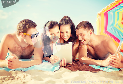 Image of group of smiling people with tablet pc on beach