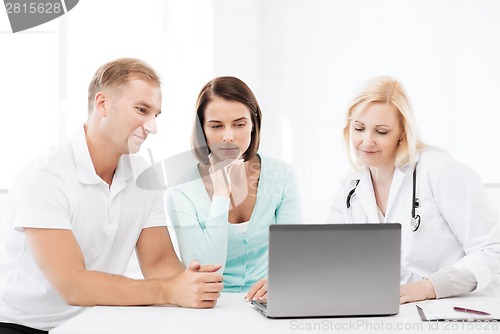 Image of doctor with patients looking at laptop