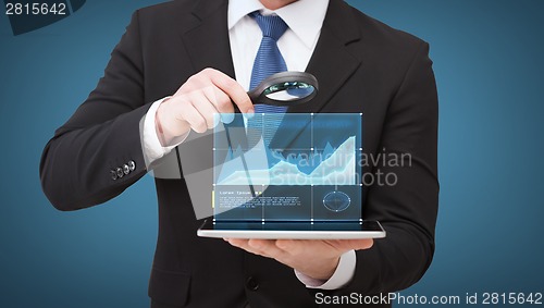 Image of businessman hand holding magnifier over tablet pc