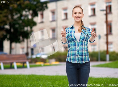 Image of young woman in casual clothes showing thumbs up