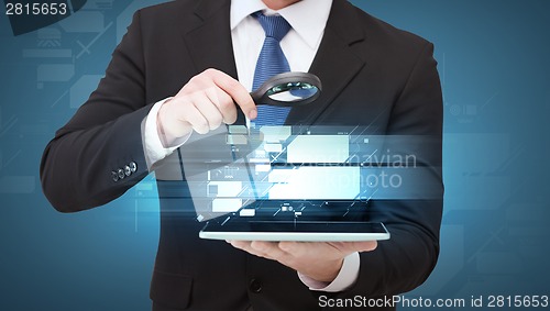 Image of businessman hand holding magnifier over tablet pc