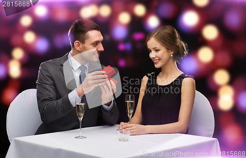 Image of excited young woman looking at boyfriend with box