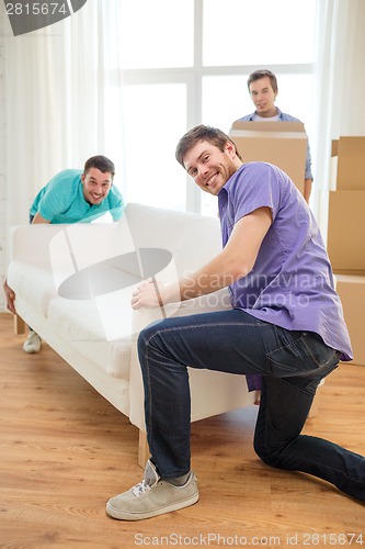 Image of smiling friends with sofa and boxes at new home