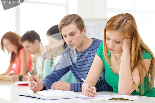 Image of tired students with textbooks and books at school