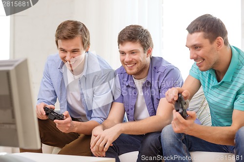 Image of smiling friends playing video games at home