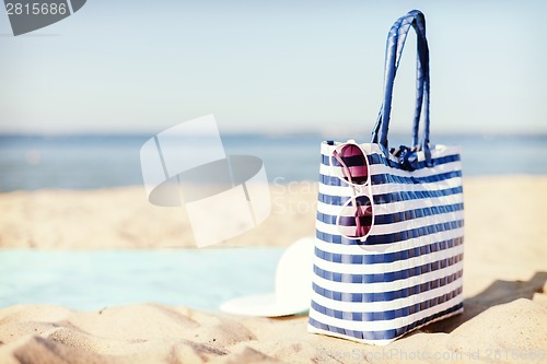 Image of straw hat, sunglasses and bag lying in the sand