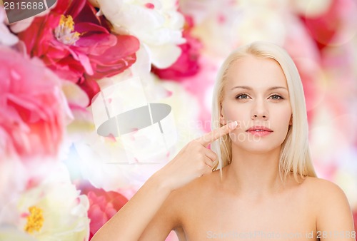 Image of calm young woman pointing at her cheek