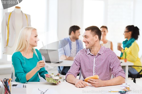 Image of smiling fashion designers having lunch at office