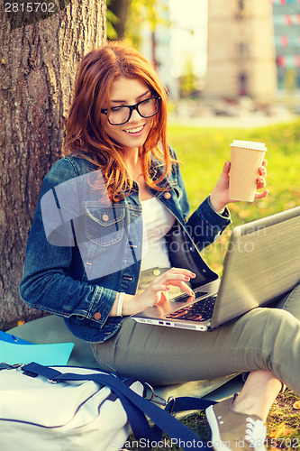 Image of teenager in eyeglasses with laptop and coffee