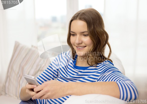 Image of smiling teenage girl with smartphone at home