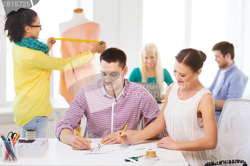 Image of smiling fashion designers working in office