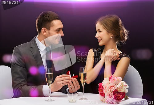 Image of man proposing to his girlfriend at restaurant