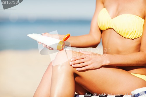 Image of girl putting sun protection cream on beach chair