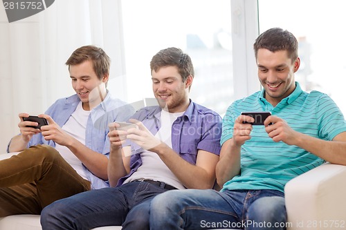 Image of smiling friends with smartphones at home