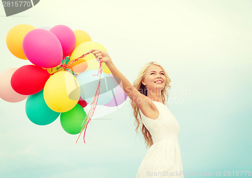 Image of smiling woman with colorful balloons outside