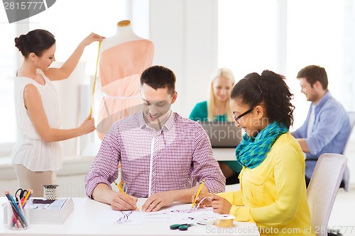 Image of smiling fashion designers working in office