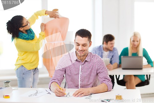 Image of smiling fashion designers working in office