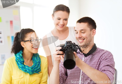 Image of smiling team with photocamera working in office