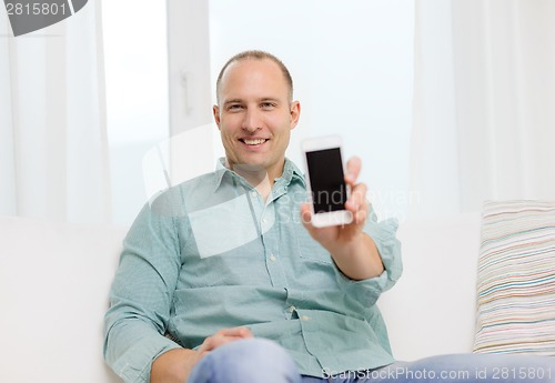 Image of smiling man with smartphone at home