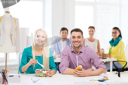 Image of smiling fashion designers having lunch at office