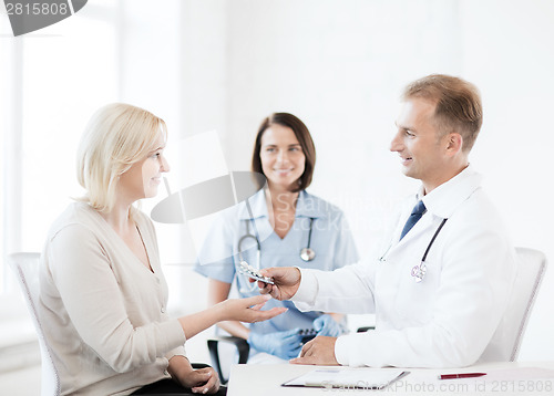 Image of doctor giving tablets to patient in hospital