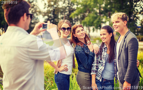 Image of teenagers taking photo with digital camera outside