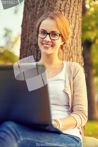 Image of smiling teenager in eyeglasses with laptop