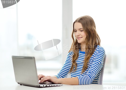 Image of smiling teenage gitl with laptop computer at home