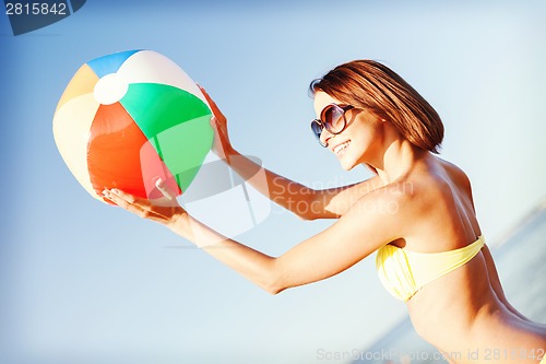 Image of girl in bikini playing ball on the beach