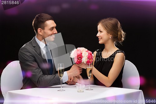 Image of smiling man giving flower bouquet to woman